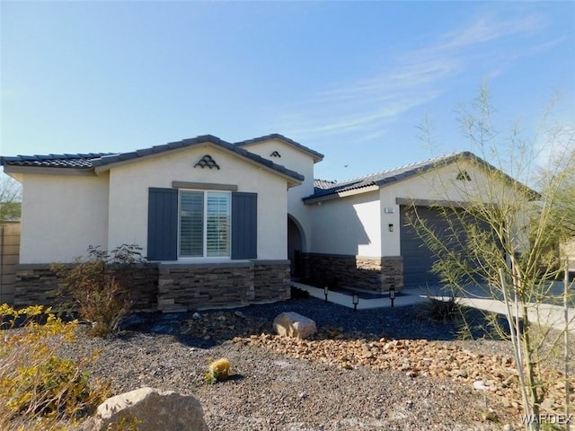 view of side of property featuring a garage, stone siding, a tile roof, and stucco siding