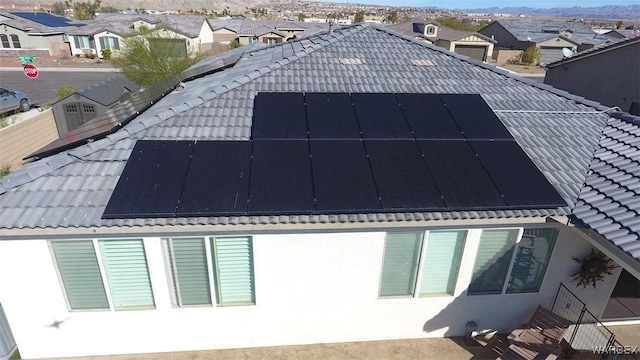 view of home's exterior featuring solar panels, a tiled roof, and a residential view