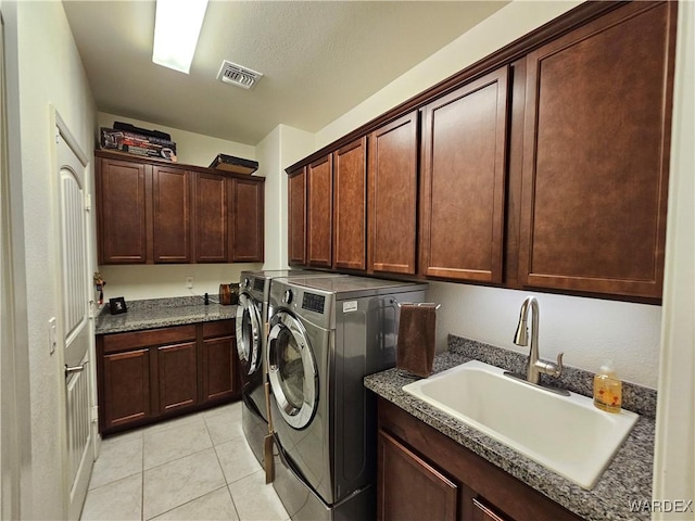 washroom with light tile patterned floors, cabinet space, visible vents, washing machine and dryer, and a sink