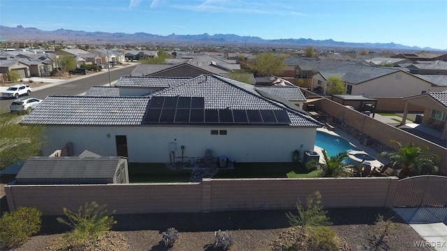 back of house featuring a tile roof, a residential view, a mountain view, and solar panels