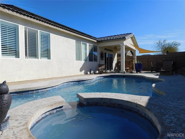 view of pool with a pool with connected hot tub, fence, and a patio