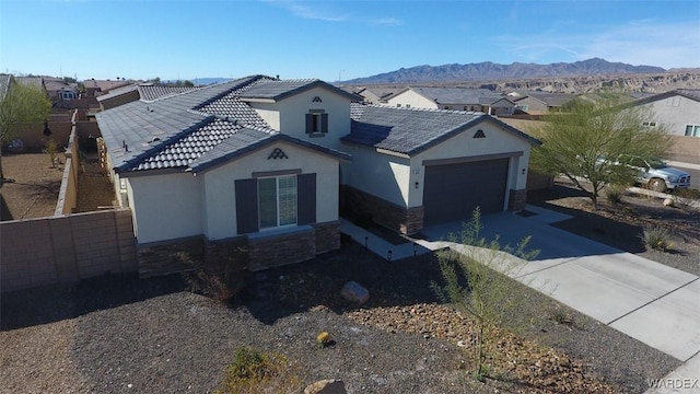 view of front of property featuring an attached garage, a mountain view, stone siding, concrete driveway, and a residential view