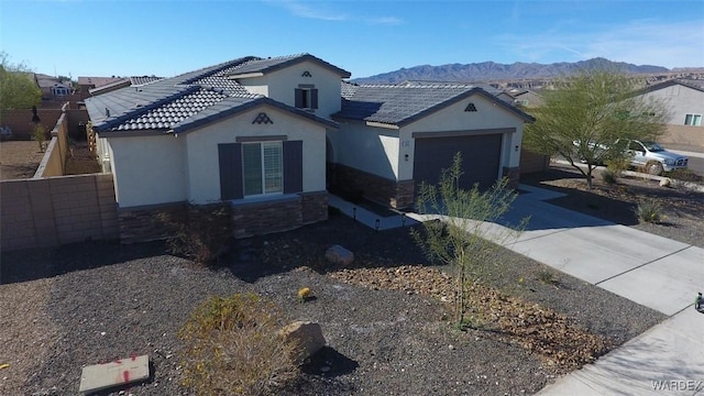 view of front facade featuring an attached garage, stone siding, driveway, and a mountain view