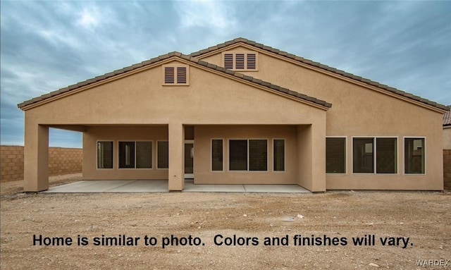 rear view of house featuring a patio, fence, and stucco siding