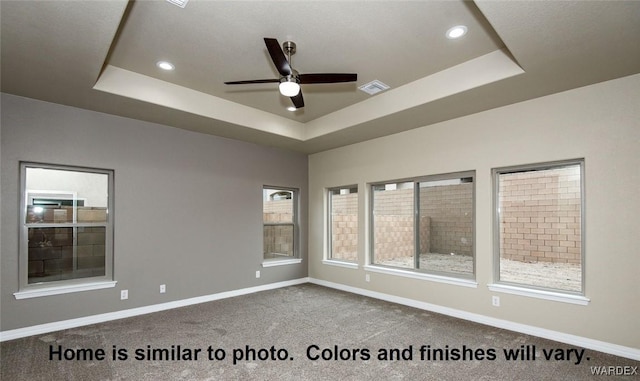 empty room featuring a tray ceiling, carpet, visible vents, and baseboards