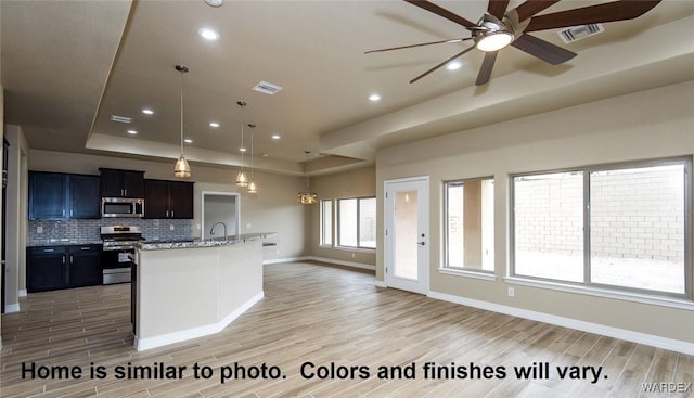 kitchen with stainless steel appliances, a raised ceiling, visible vents, backsplash, and open floor plan