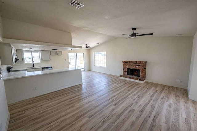 1925 E Ln Entrada Pl, Fort Mohave, AZ 86426 - unfurnished living room featuring light wood-style flooring, ceiling fan, a brick fireplace, and lofted ceiling