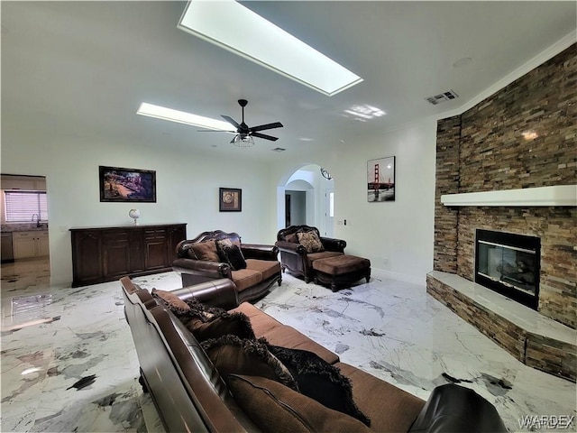 living area with marble finish floor, visible vents, a fireplace, and ceiling fan