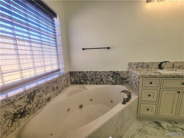 bathroom featuring marble finish floor, a tub with jets, and vanity