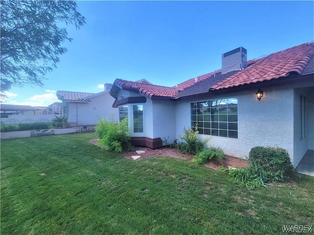 rear view of house featuring a yard, central AC unit, a tile roof, and stucco siding