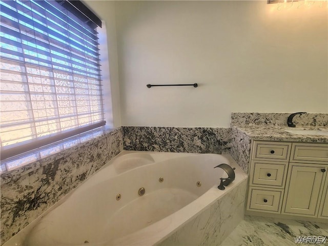 bathroom featuring marble finish floor, a tub with jets, and vanity