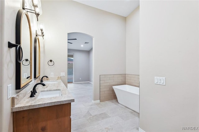 bathroom featuring double vanity, a freestanding tub, visible vents, and a sink