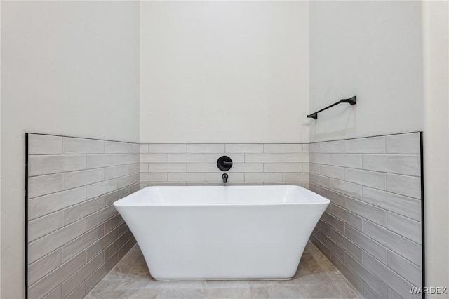 bathroom featuring a freestanding tub, tile patterned flooring, tile walls, and a wainscoted wall