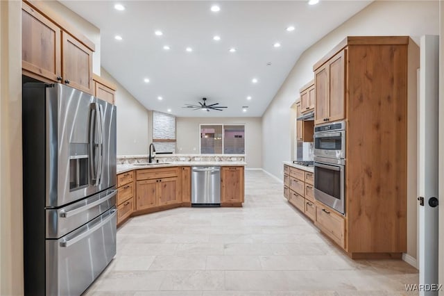 kitchen featuring brown cabinets, a peninsula, stainless steel appliances, light countertops, and a sink