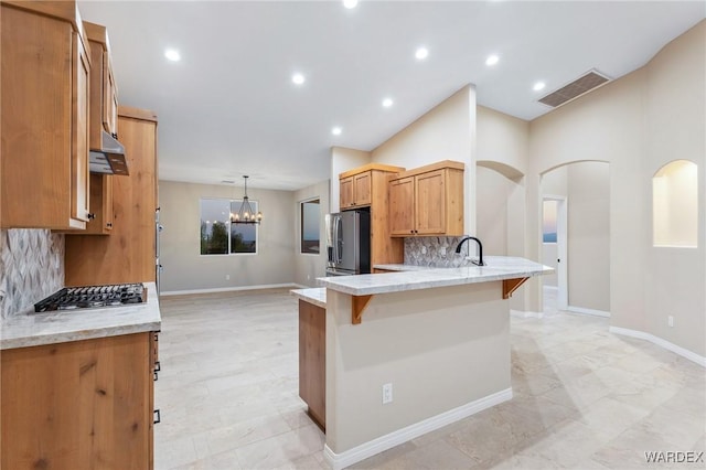 kitchen featuring arched walkways, stainless steel appliances, visible vents, a peninsula, and a kitchen breakfast bar