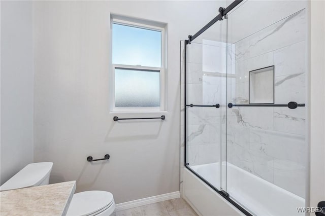 bathroom featuring marble finish floor, shower / bath combination with glass door, toilet, vanity, and baseboards