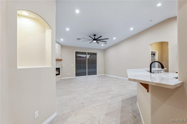 unfurnished living room featuring a ceiling fan, recessed lighting, a stone fireplace, and baseboards