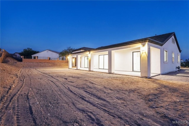 view of side of property featuring a patio, fence, and stucco siding