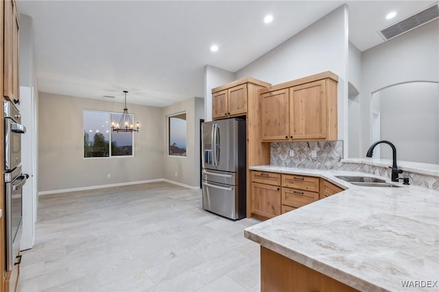 kitchen with a sink, visible vents, appliances with stainless steel finishes, tasteful backsplash, and pendant lighting