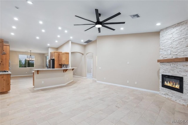 kitchen featuring freestanding refrigerator, open floor plan, visible vents, and a stone fireplace