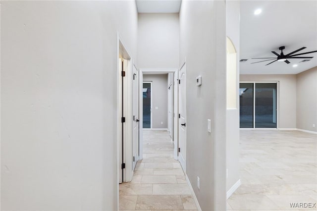 hall featuring recessed lighting, a towering ceiling, and baseboards