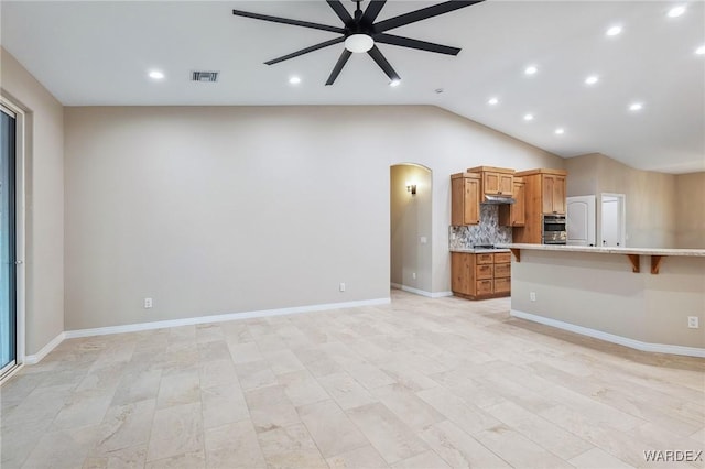 unfurnished living room featuring arched walkways, visible vents, a ceiling fan, vaulted ceiling, and baseboards