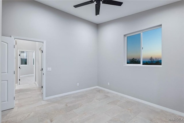 unfurnished room with ceiling fan and baseboards