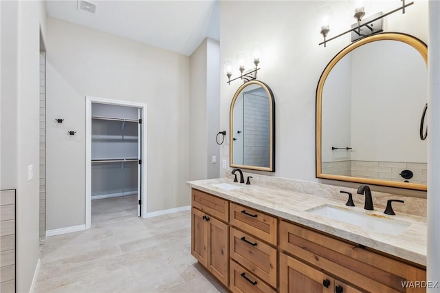 bathroom with double vanity, a spacious closet, visible vents, and a sink