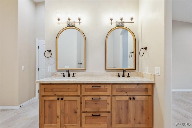 bathroom with double vanity, baseboards, and a sink