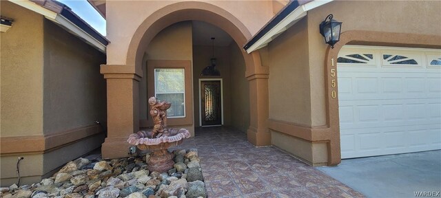 entrance to property featuring an attached garage and stucco siding