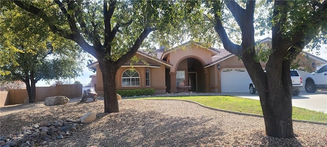 view of front facade featuring stucco siding, fence, a garage, driveway, and a tiled roof