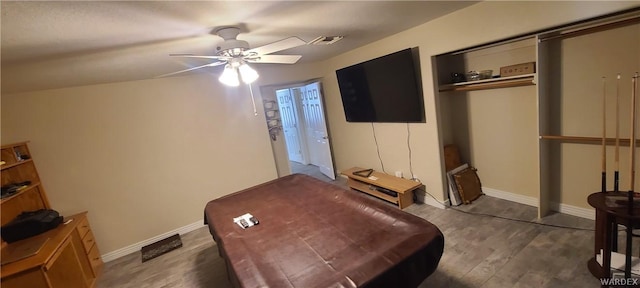 bedroom featuring baseboards, visible vents, dark wood finished floors, ceiling fan, and a closet