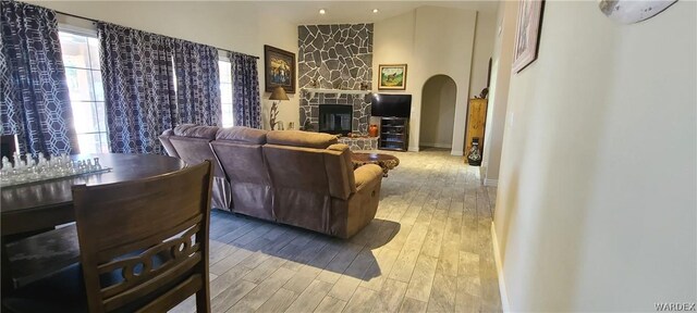 living area featuring a fireplace, arched walkways, and wood finished floors