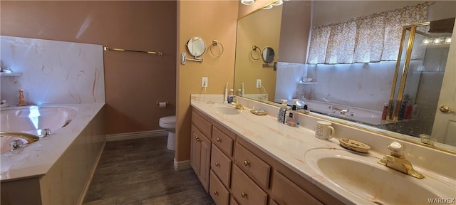 bathroom with toilet, a sink, baseboards, a bath, and double vanity