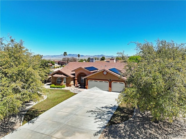 view of front of property featuring driveway, a tile roof, an attached garage, a mountain view, and stucco siding