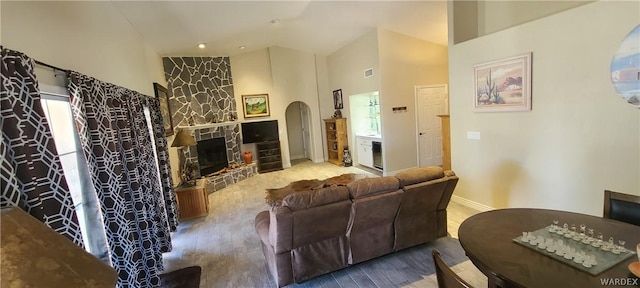 living area featuring arched walkways, a fireplace, wood finished floors, visible vents, and a towering ceiling