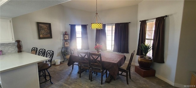 dining space featuring vaulted ceiling, dark wood-type flooring, and baseboards