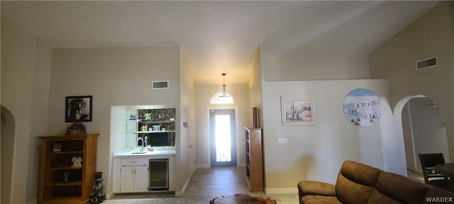 foyer entrance featuring bar area, beverage cooler, visible vents, and arched walkways