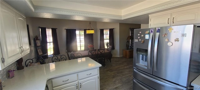 kitchen featuring white cabinetry, light countertops, hanging light fixtures, stainless steel refrigerator with ice dispenser, and a raised ceiling