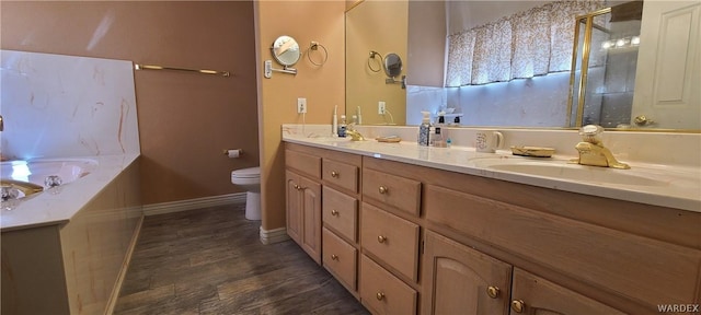 bathroom with toilet, wood finished floors, a sink, baseboards, and double vanity