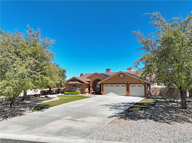 view of front of house featuring an attached garage, driveway, a chimney, and stucco siding