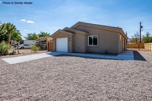 view of front facade featuring a garage, stucco siding, driveway, and fence