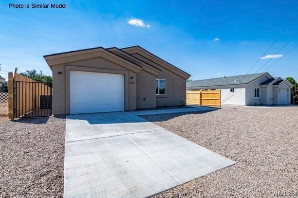 view of front of property with a garage, concrete driveway, fence, and stucco siding