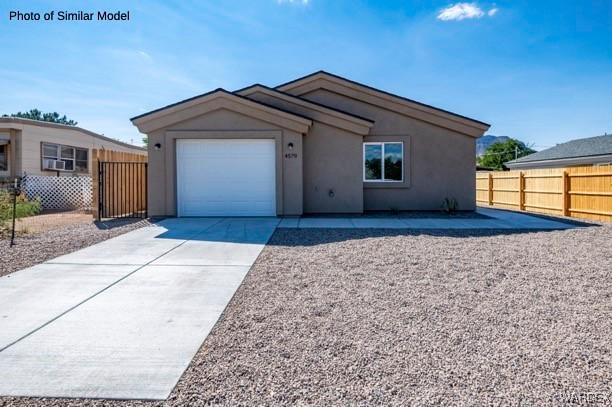 ranch-style home with concrete driveway, fence, an attached garage, and stucco siding