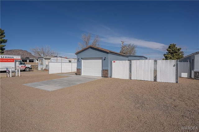 garage featuring concrete driveway and fence