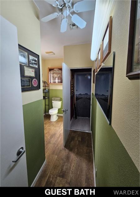 corridor featuring baseboards, visible vents, and dark wood finished floors