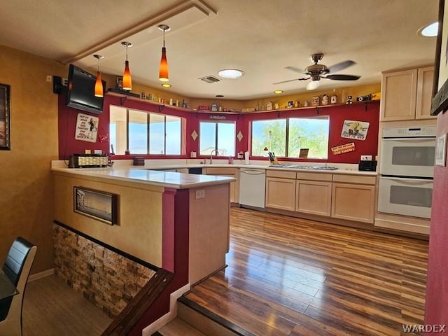 kitchen featuring a peninsula, white appliances, light countertops, and hanging light fixtures