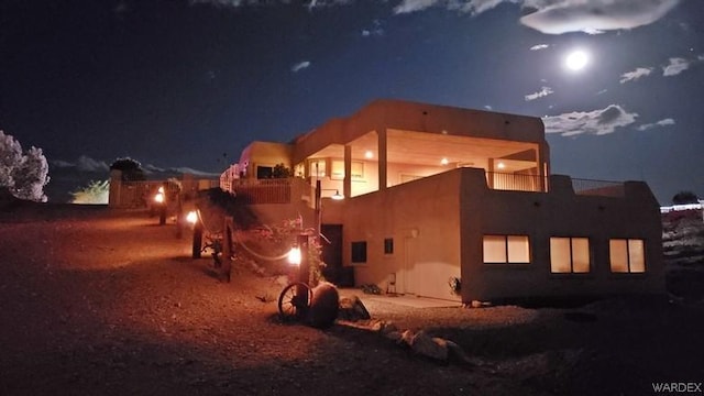 back of house at night with a balcony