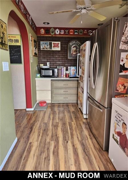 kitchen featuring black microwave, wood finished floors, a ceiling fan, light countertops, and freestanding refrigerator