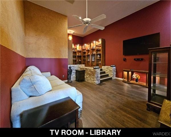 living room with ceiling fan, a fireplace, wood finished floors, and baseboards